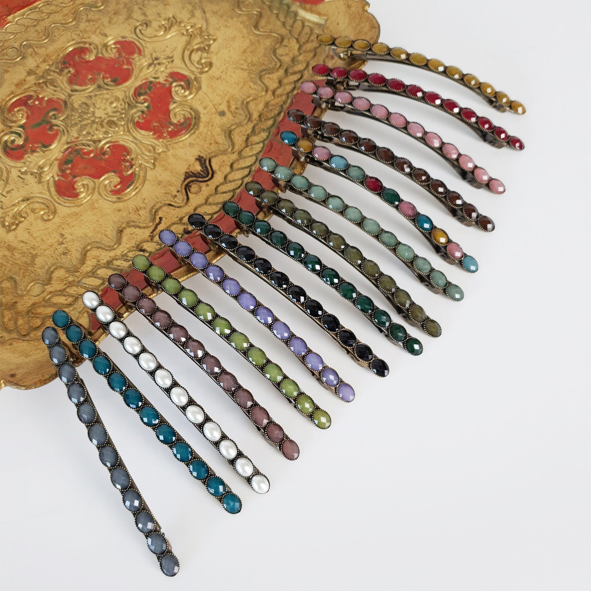 Long vintage style antique brass French barrette featuring a row of small glossy oval acetate stones. 4.1 inch skinny retro hair clip for half-up and ponytail styling.