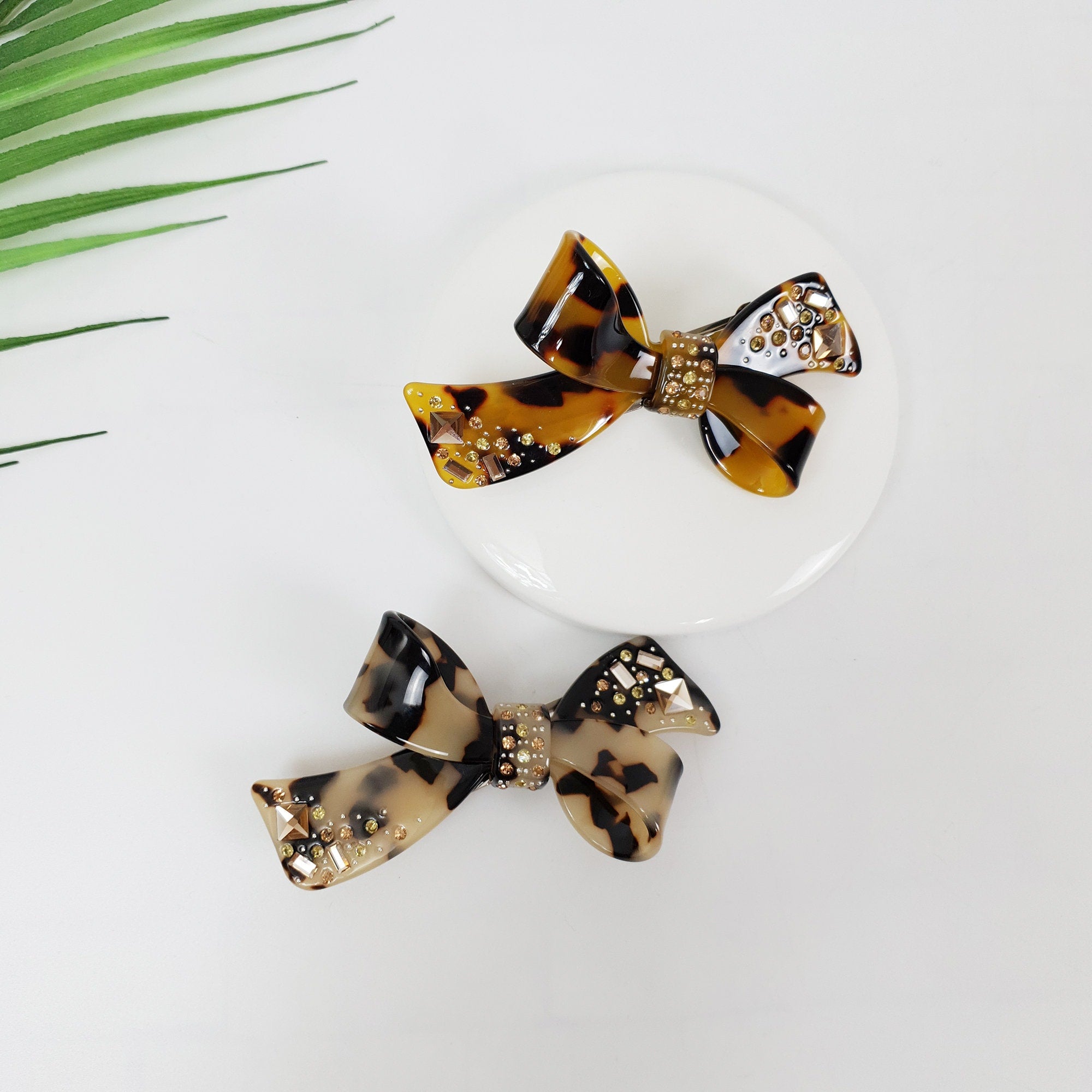 Cellulose acetate tortoise shell hair barrette featuring a double bow design with sparkling rhinestone accents for side hair styling.