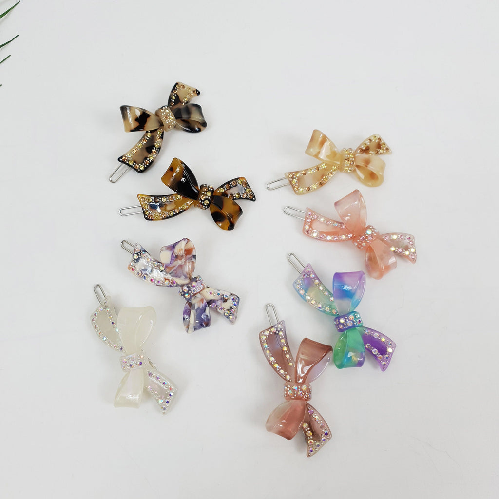 Cellulose acetate double bow hair clip with cubic zirconia crystals. Tortoise shell and marble pattern snap barrette for side hair and bangs.