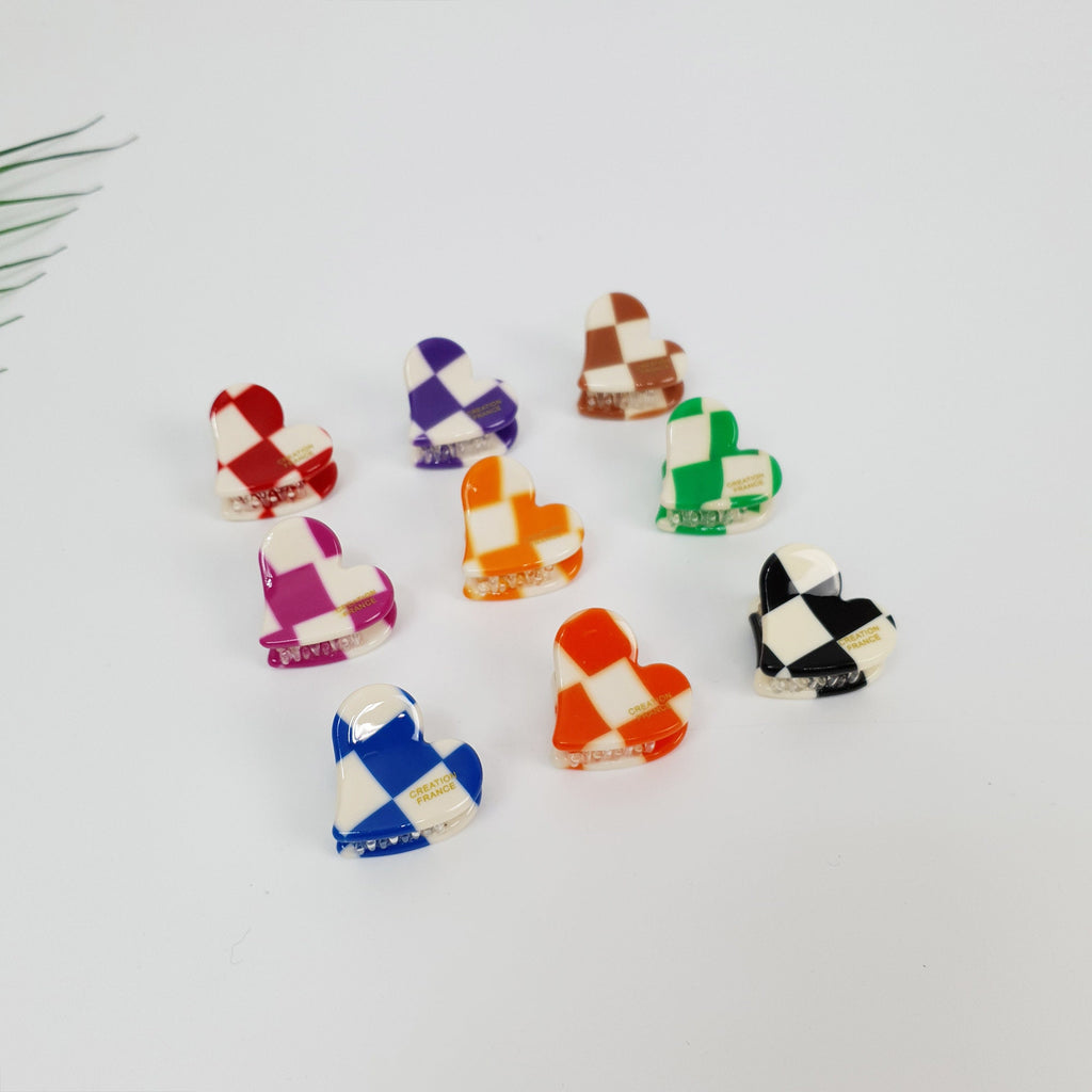 Cellulose acetate mini claw clip in heart shape with checkerboard pattern. 1 inch small jaw clip for bangs in red, blue, and black. Cute retro mod style hair accessory for women.