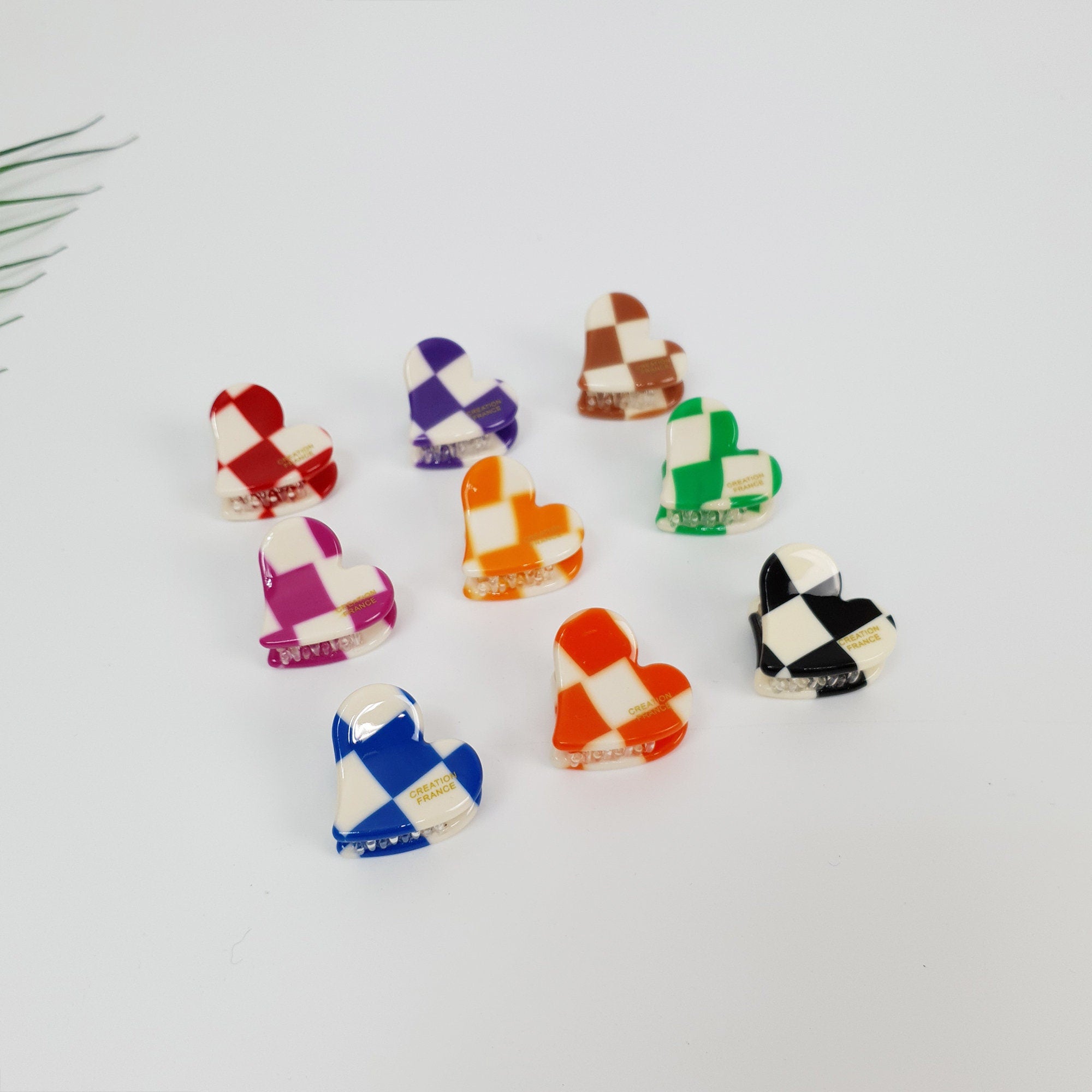 Cellulose acetate mini claw clip in heart shape with checkerboard pattern. 1 inch small jaw clip for bangs in red, blue, and black. Cute retro mod style hair accessory for women.