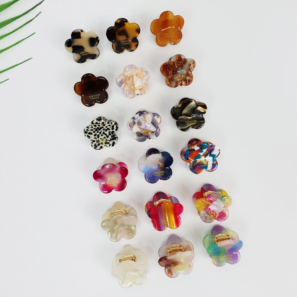Miniature cellulose acetate hair claw in tortoise and pastel colors, 2.5cm daisy flower shape for styling bangs, non-slip tiny jaw clip for side hair. A collection of 15 colorful flower-shaped hair clips. The clips are made of plastic and have a variety of patterns, including leopard print, stripes, and swirls. The clips are all in different colors, including pink, purple, blue, green, orange, and brown. The clips have the words 'CREATION FRANCE' printed on them.