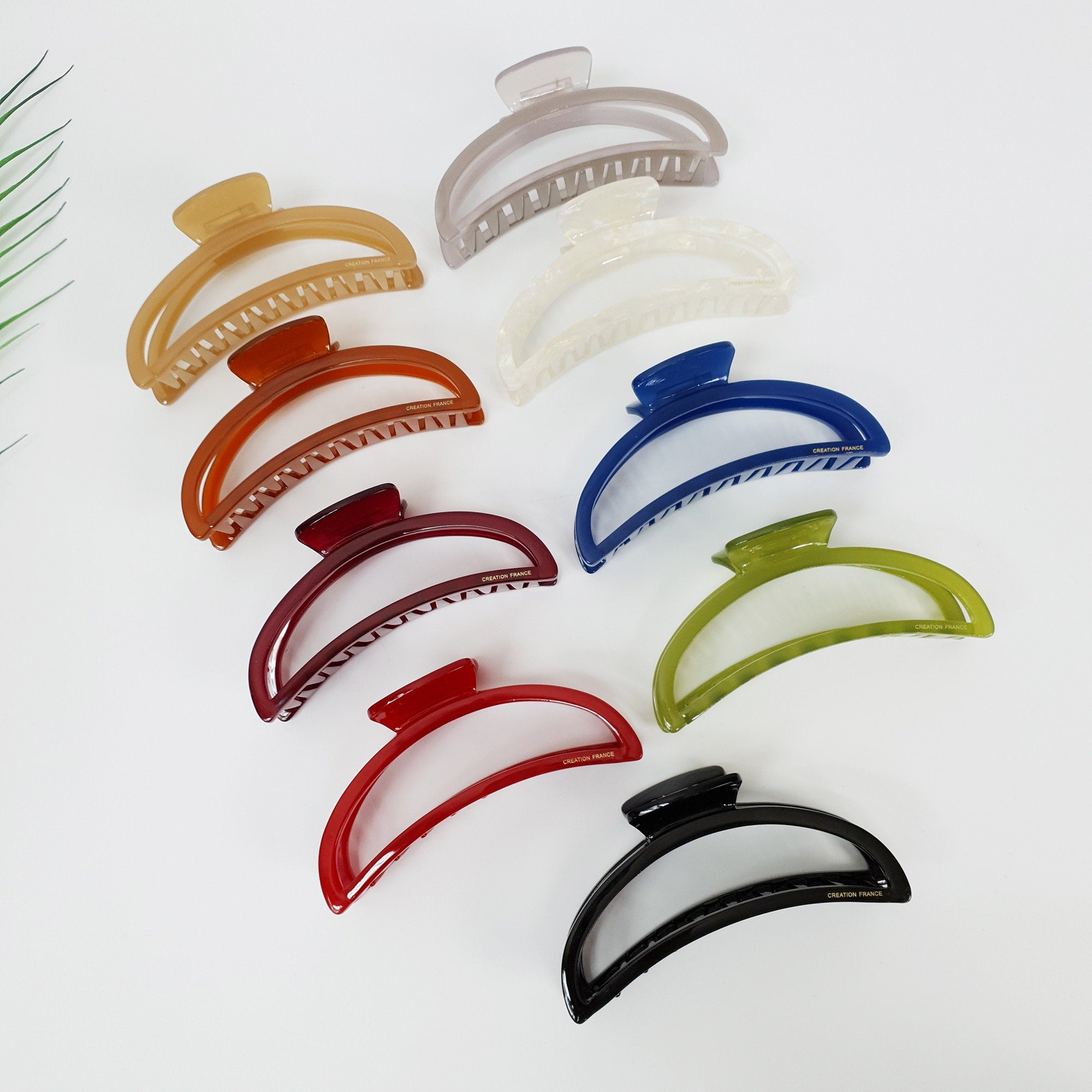 Cellulose Acetate Large Hair Claw Clip Half Moon Shape Minimalist Style for Thick Hair Updo A collection of eight hair clips in various colors including beige, brown, red, green, blue, and black. The clips are all made of plastic and have a curved shape. The clips are designed to hold hair in place.