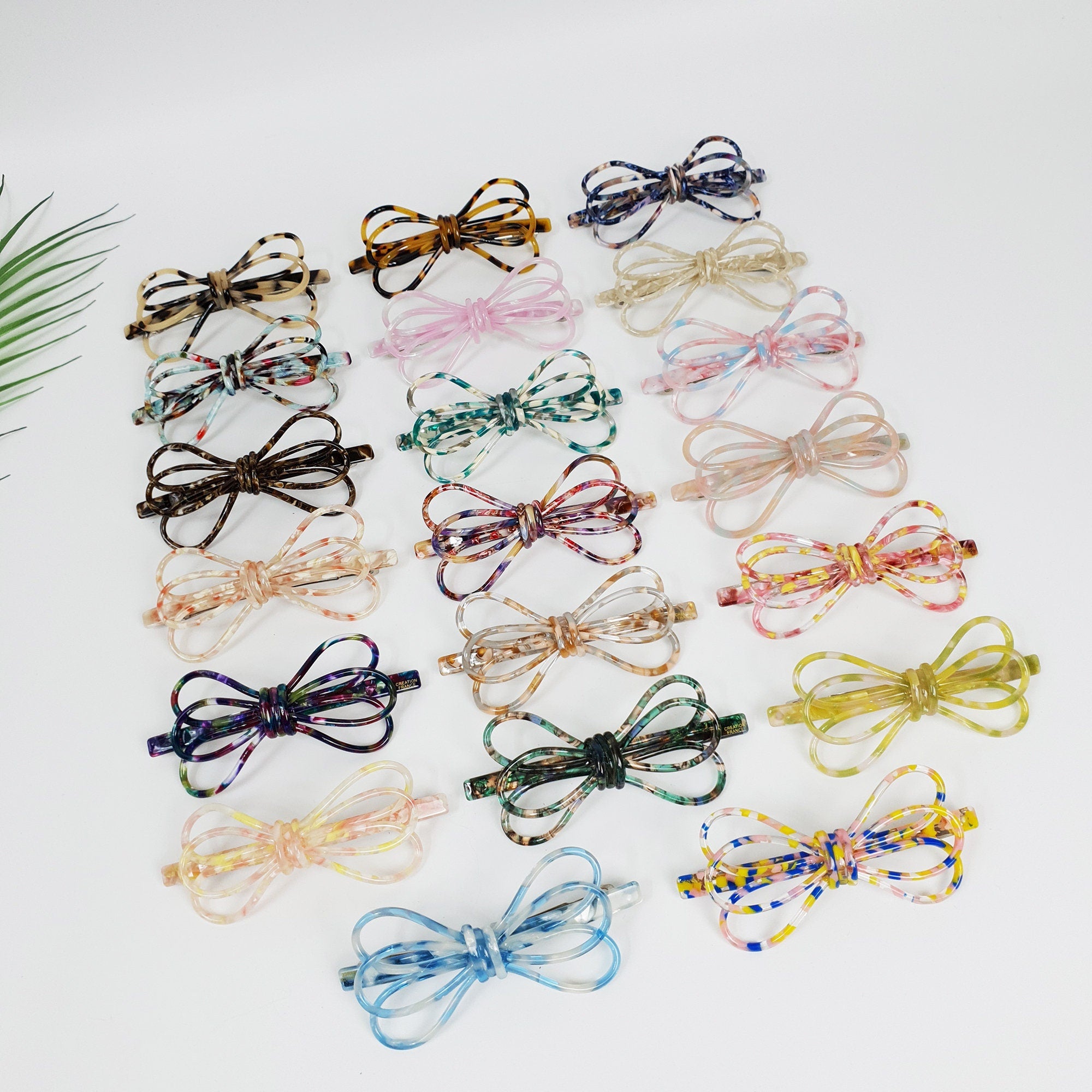 Long cellulose acetate barrette featuring a triple loop ribbon design. Marble and tortoise shell pattern automatic hair clip for ponytails.