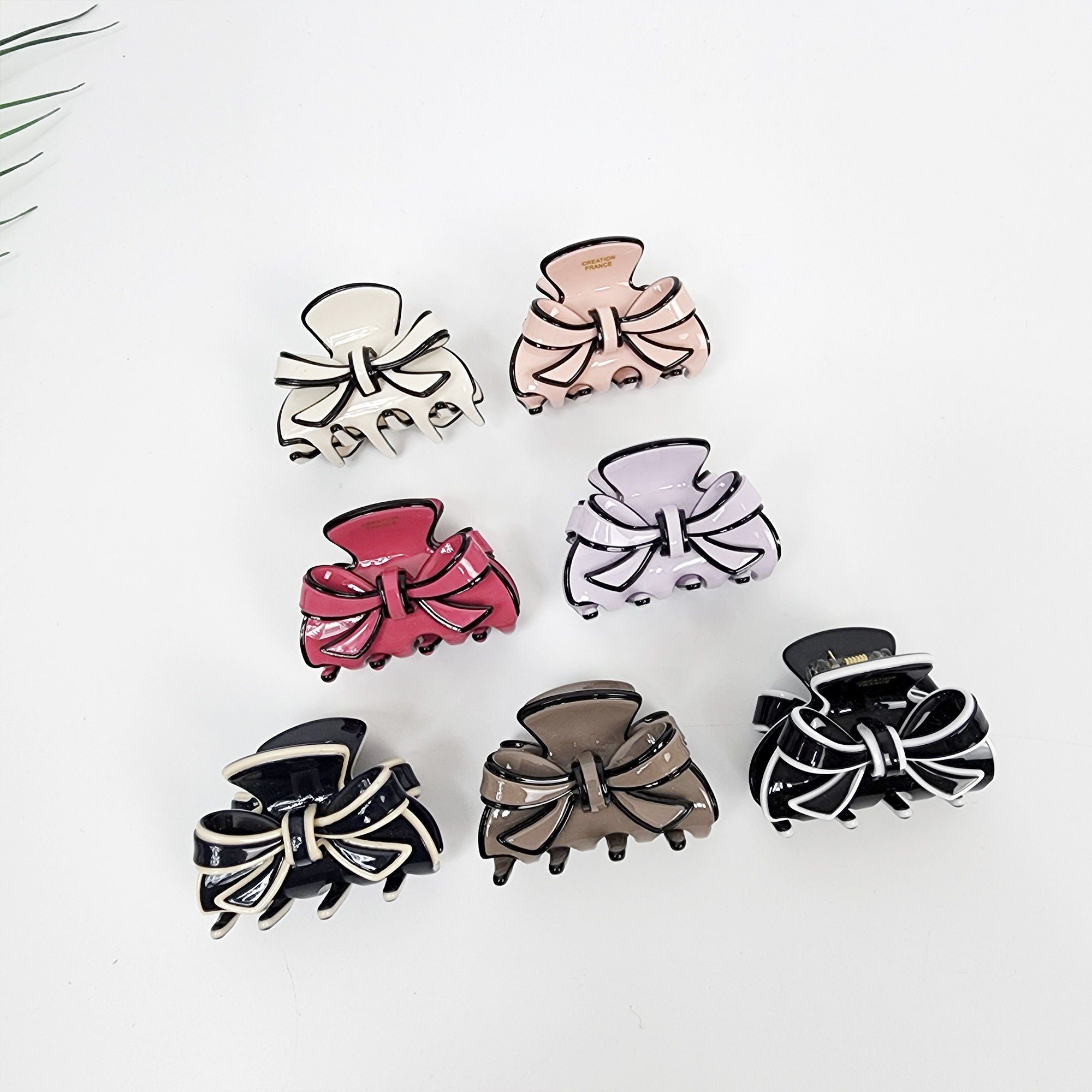 Small cellulose acetate ribbon hair claw clip in pastel colors. Bow shaped mini jaw clamp. 1.8 inch hair accessory for half updos and side bangs. Seven hair clips with black and white bows. The clips are in various colors including white, pink, purple, red, brown, and black.