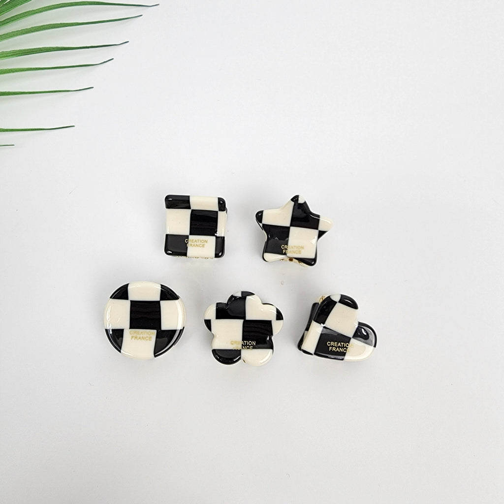 Cellulose acetate mini hair claw clip in black and white checkerboard pattern, geometric small hair clamp for bangs, Mod style cute accessories.  Five black and white checkered hair clips in different shapes: square, star, circle, flower, and heart. Each clip has the words 'CREATION FRANCE' printed on the back.