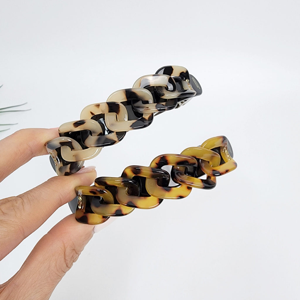 Cellulose acetate chain link barrette. Classic 3.5 inch tortoise shell french hair clip for elegant half-up hairstyles. Two brown and cream colored plastic hair clips shaped like a chain link. The hair clips are made of a tortoiseshell pattern.