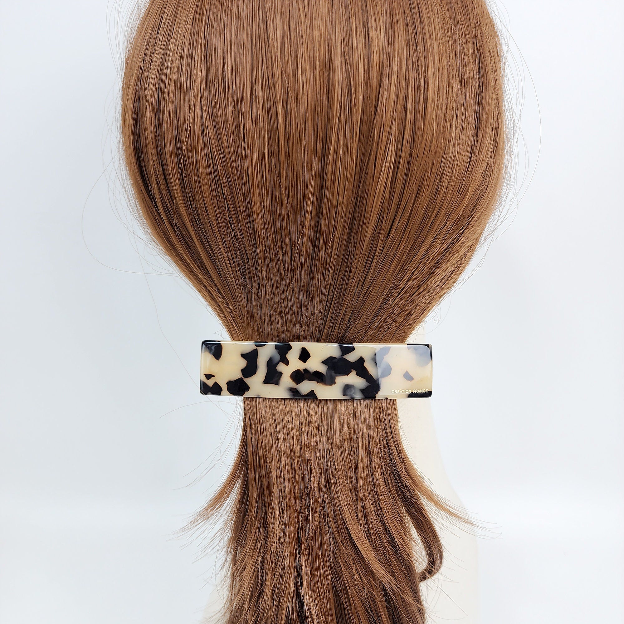 Cellulose acetate rectangular hair barrette in tortoise shell pattern for women styling a low ponytail or half updo.