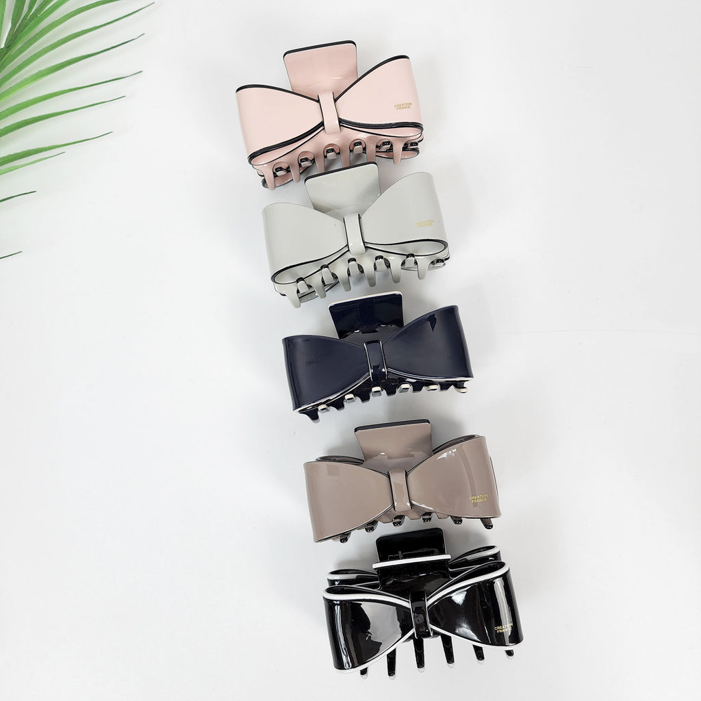 Cellulose acetate ribbon bow hair claw clip in pastel and black colors, elegant half-up hairstyle accessory for women.