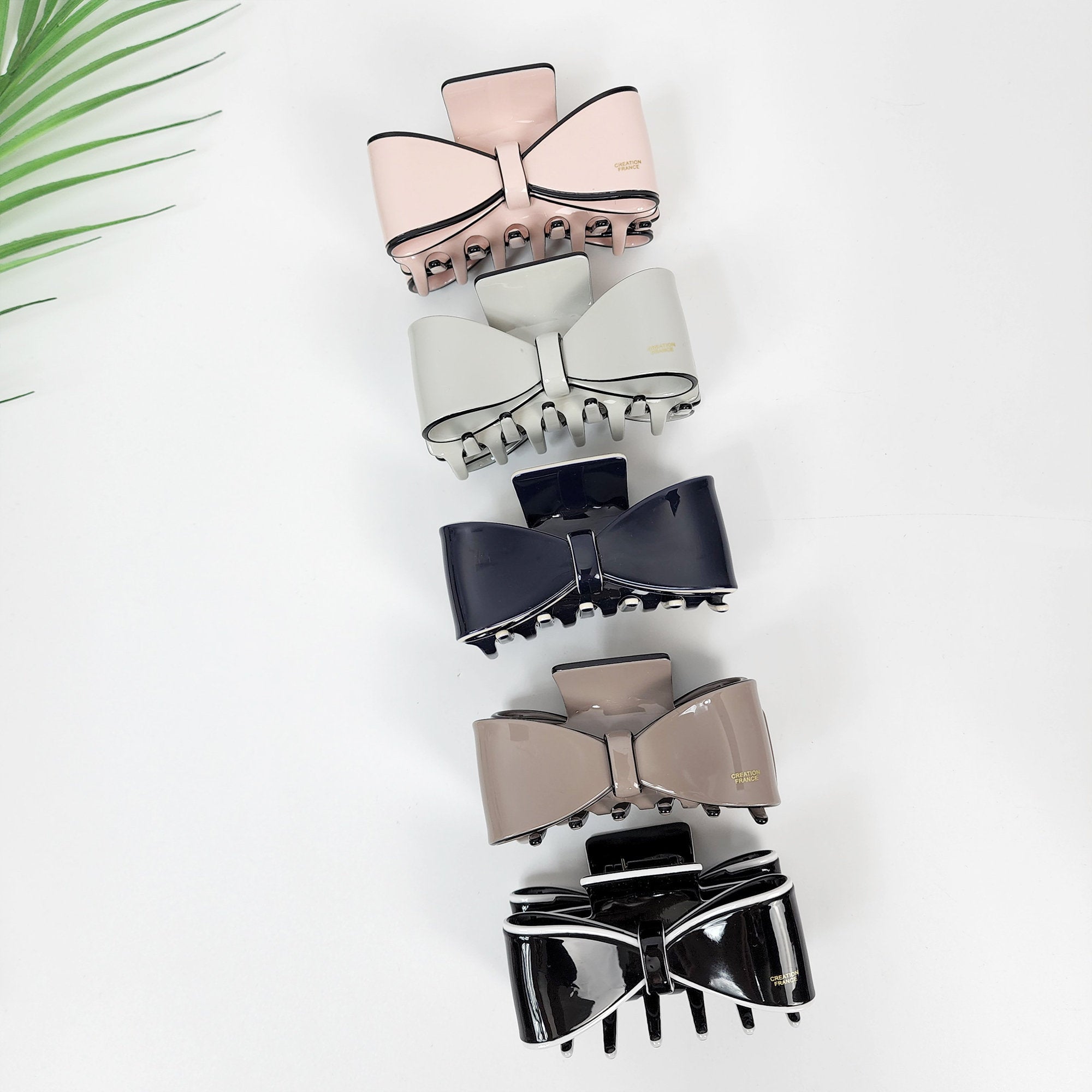 Cellulose acetate ribbon bow hair claw clip in pastel and black colors, elegant half-up hairstyle accessory for women.