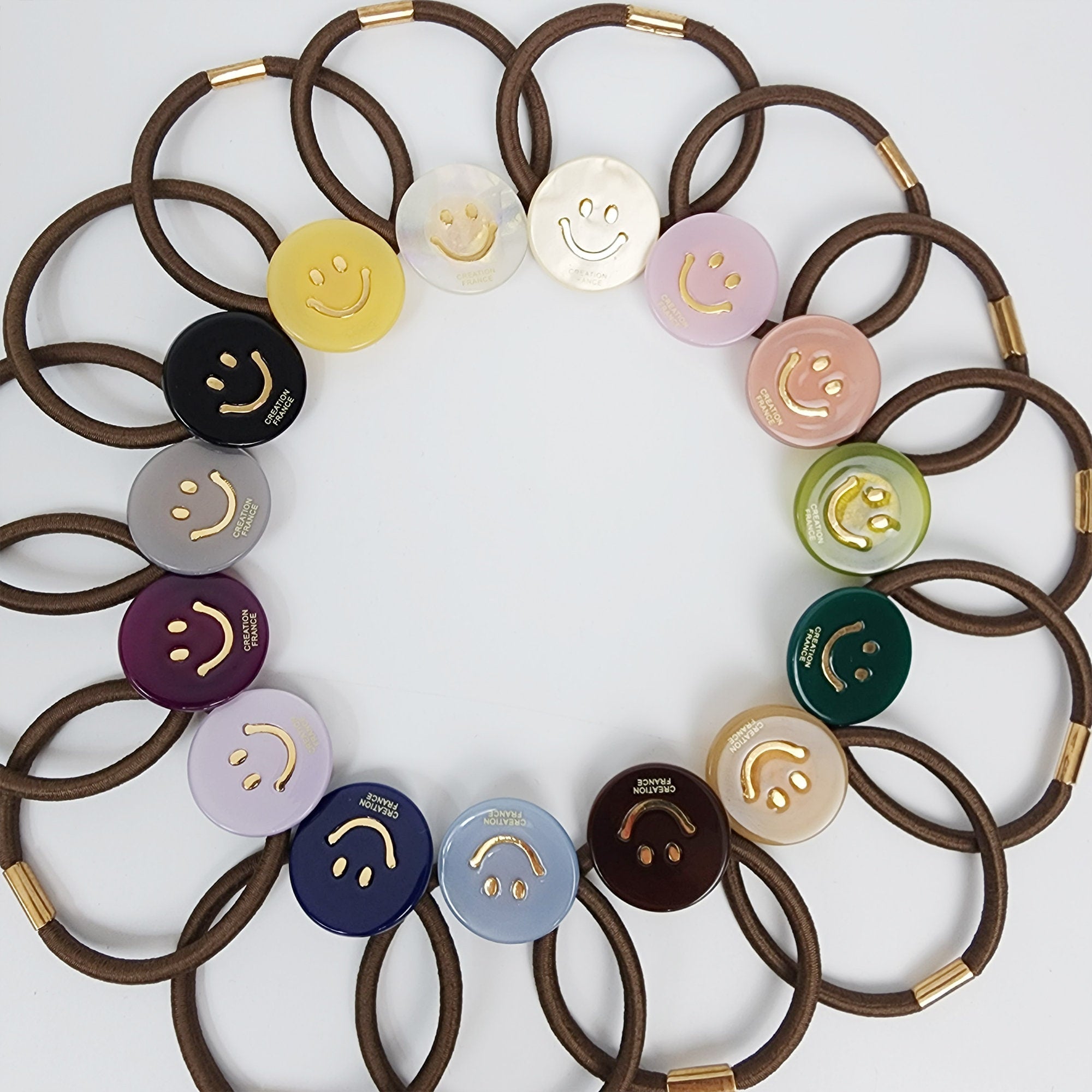 Glossy cellulose acetate round hair tie with gold smiley face inlay. 1 inch happy face ponytail holder in pastel and neutral colors. Cute preppy hair accessory for girls and women birthday gift.