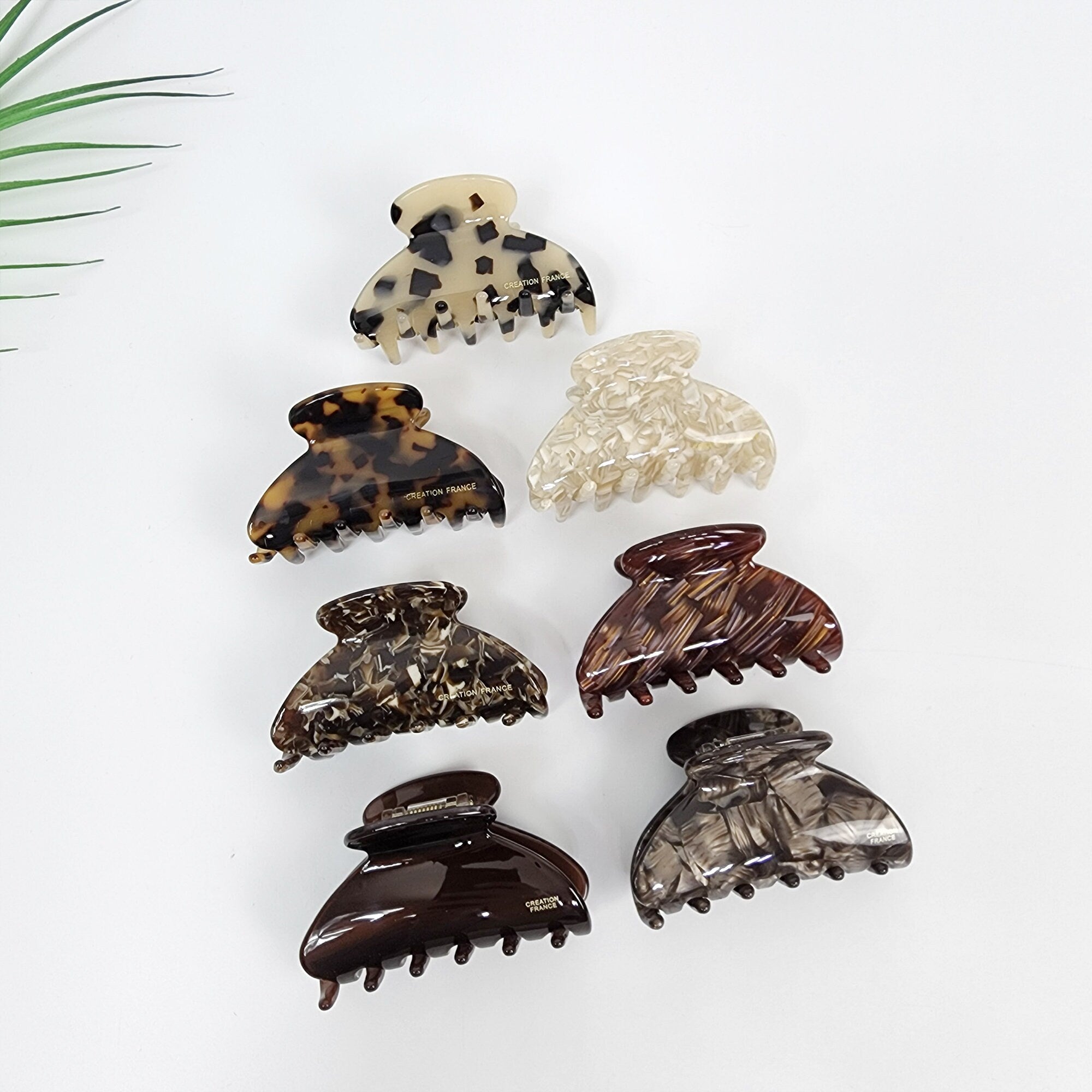 Cellulose acetate half moon hair claw clip featuring tortoise shell and marble patterns. Small 2.6 inch jaw clip designed for secure half-up hairstyles. Six different patterned hair clips. The clips are made of brown, black, and white plastic. The clips have a claw shape with five prongs. The clips are all different patterns, including tortoise shell, leopard print, and marble.