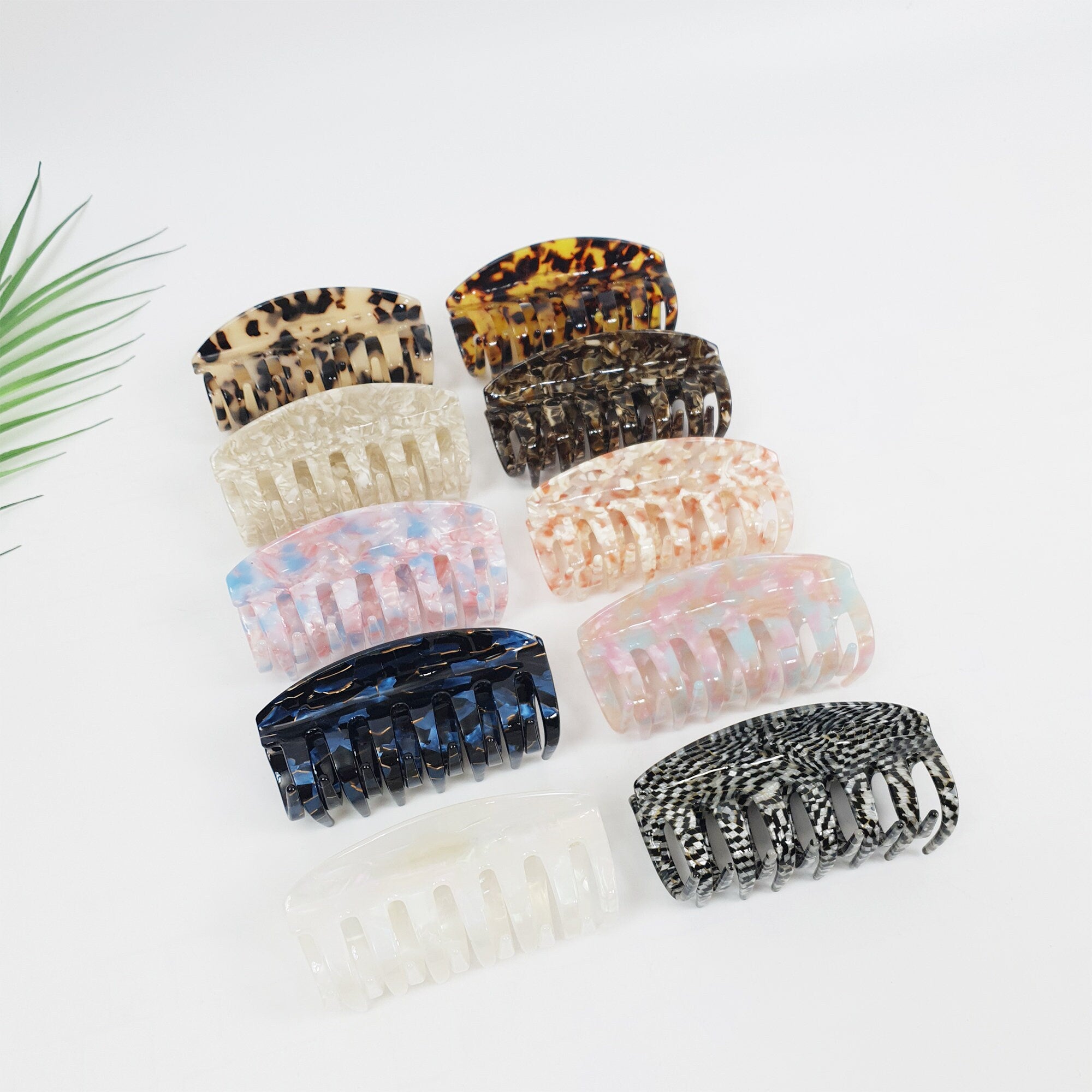 Cellulose acetate hair claw clip in tortoise shell and marble patterns holding a thick hair updo. Rectangular jaw clip accessories for women.