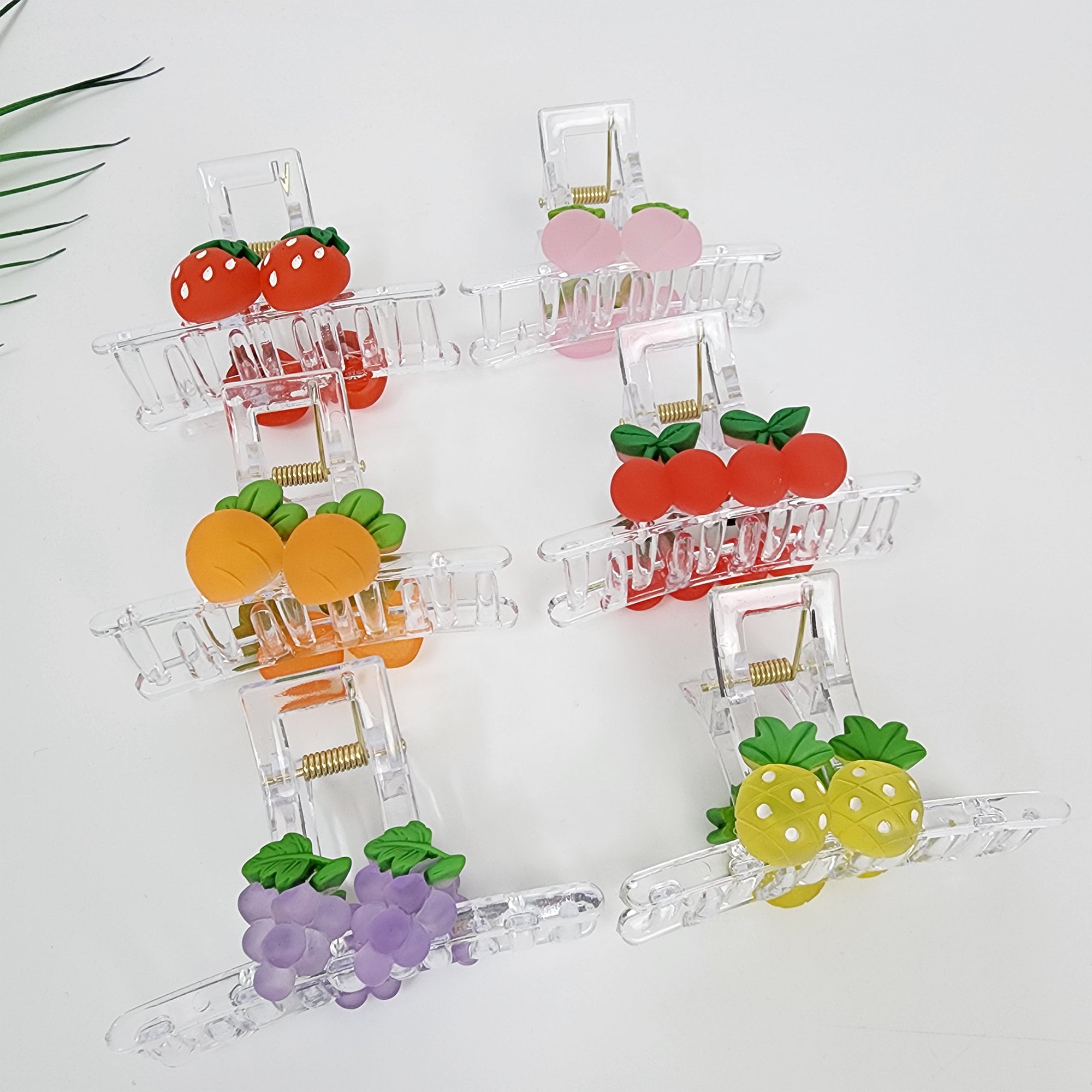 Clear acrylic hair claw clip with cute fruit charms strawberry carrot grape peach cherry pineapple summer hair accessory.  Six clear plastic hair clips with different fruit designs. The clips are all the same shape and size. The fruit designs include strawberries, peaches, cherries, oranges, grapes, and pineapples. The fruit designs are all in bright colors.