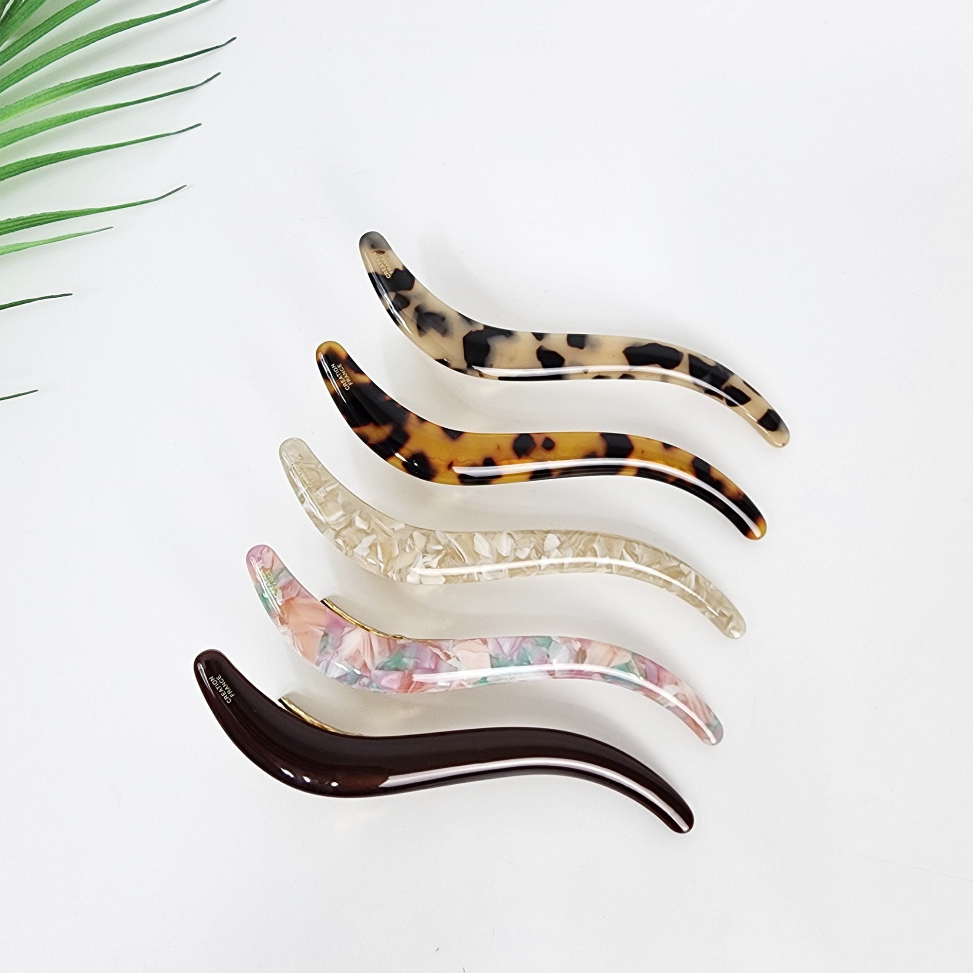 Cellulose acetate S curved alligator hair clip tortoise shell pattern long hair slide for french twist updo  Five hair clips in different colors and patterns. The clips are all curved and have a smooth, glossy finish. The colors include brown, white, pink, and black. The patterns include a leopard print, a floral print, and a speckled pattern.