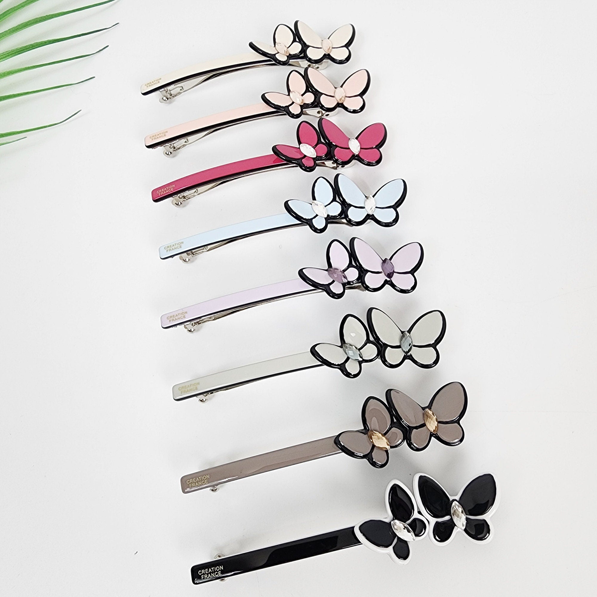 Cellulose acetate slim barrette featuring a double butterfly design with crystal accents. 3.7 inch automatic hair clip ideal for half up styles.