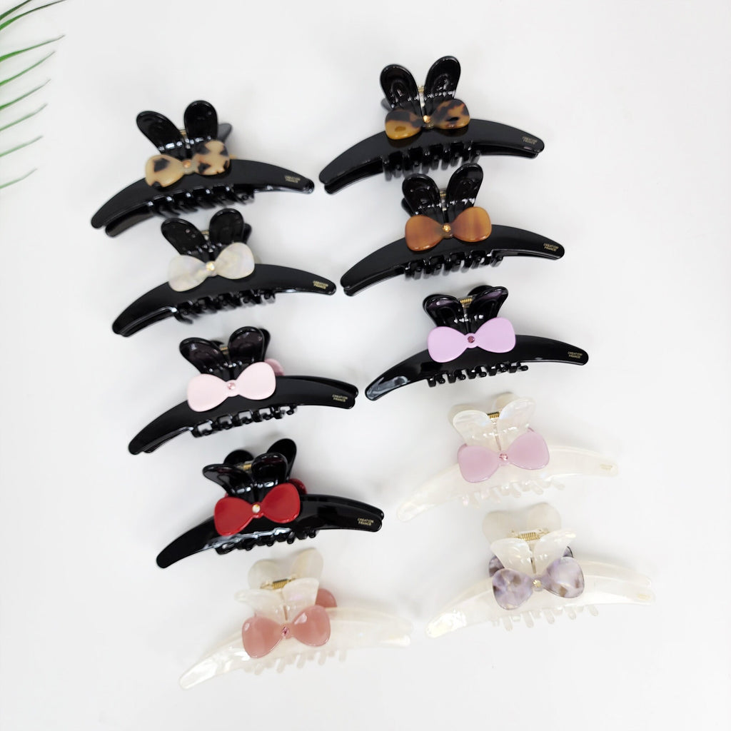 Large cellulose acetate hair claw clip featuring a cute rabbit ear ribbon design. 4.7-inch curved black and aurora jaw clips for secure updos.
