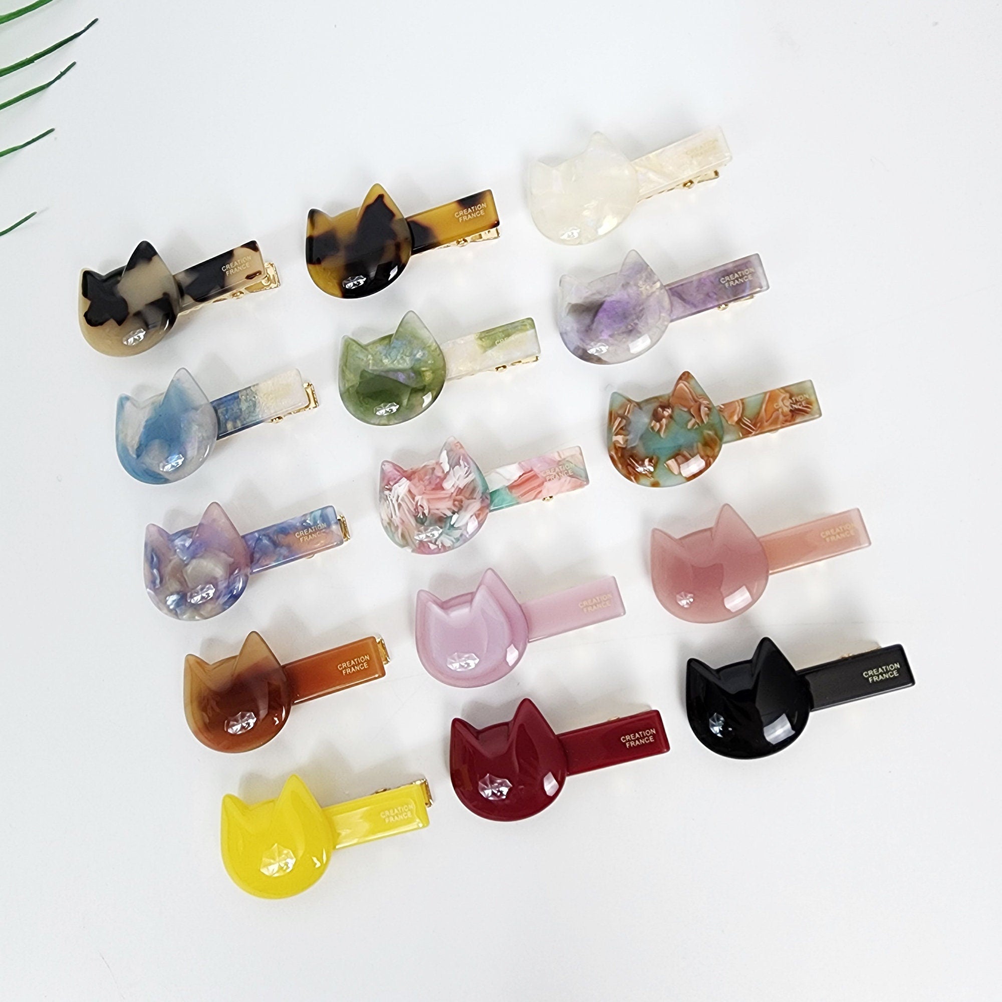 Small cellulose acetate cat shaped hair clip with gold alligator backing for bangs and side hair styling.