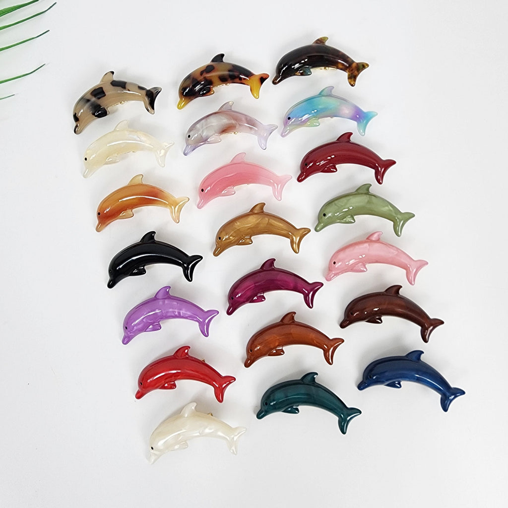 Cellulose acetate dolphin shaped hair clip, 2.2 inch alligator beak clip for side bangs, cute animal hair accessory for women. A collection of 18 dolphin hair clips in various colors including brown, white, pink, red, blue, green, purple, and black. The clips are made of plastic and have a shiny finish.