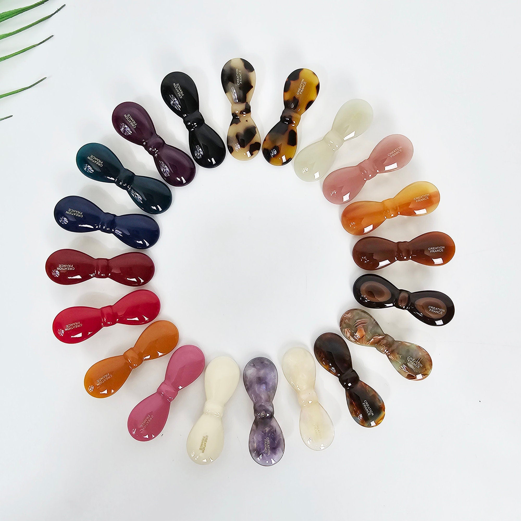 Cellulose acetate bow hair clip in tortoise shell and pink, small alligator clip for bangs, cute mini barrette for side hair. A collection of 17 assorted hair clips in various colors and patterns. The clips are all in the shape of a bow and are made of plastic. The colors include black, brown, white, pink, purple, and green. The patterns include solid colors, stripes, and polka dots.