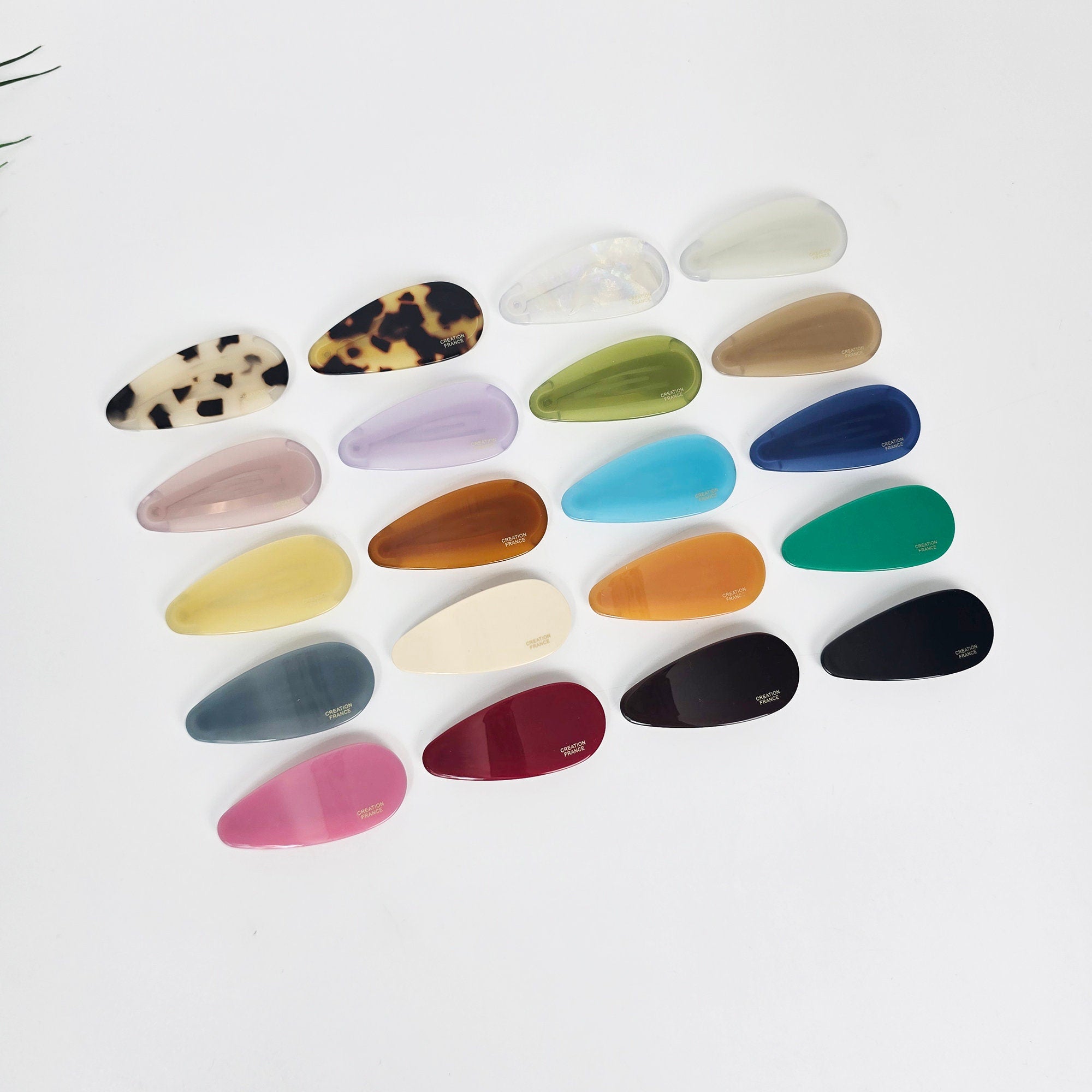 Teardrop shaped cellulose acetate snap clip in black and tortoise shell patterns. Minimalist geometric hair slide for side bangs holding, retro 90s style accessory.