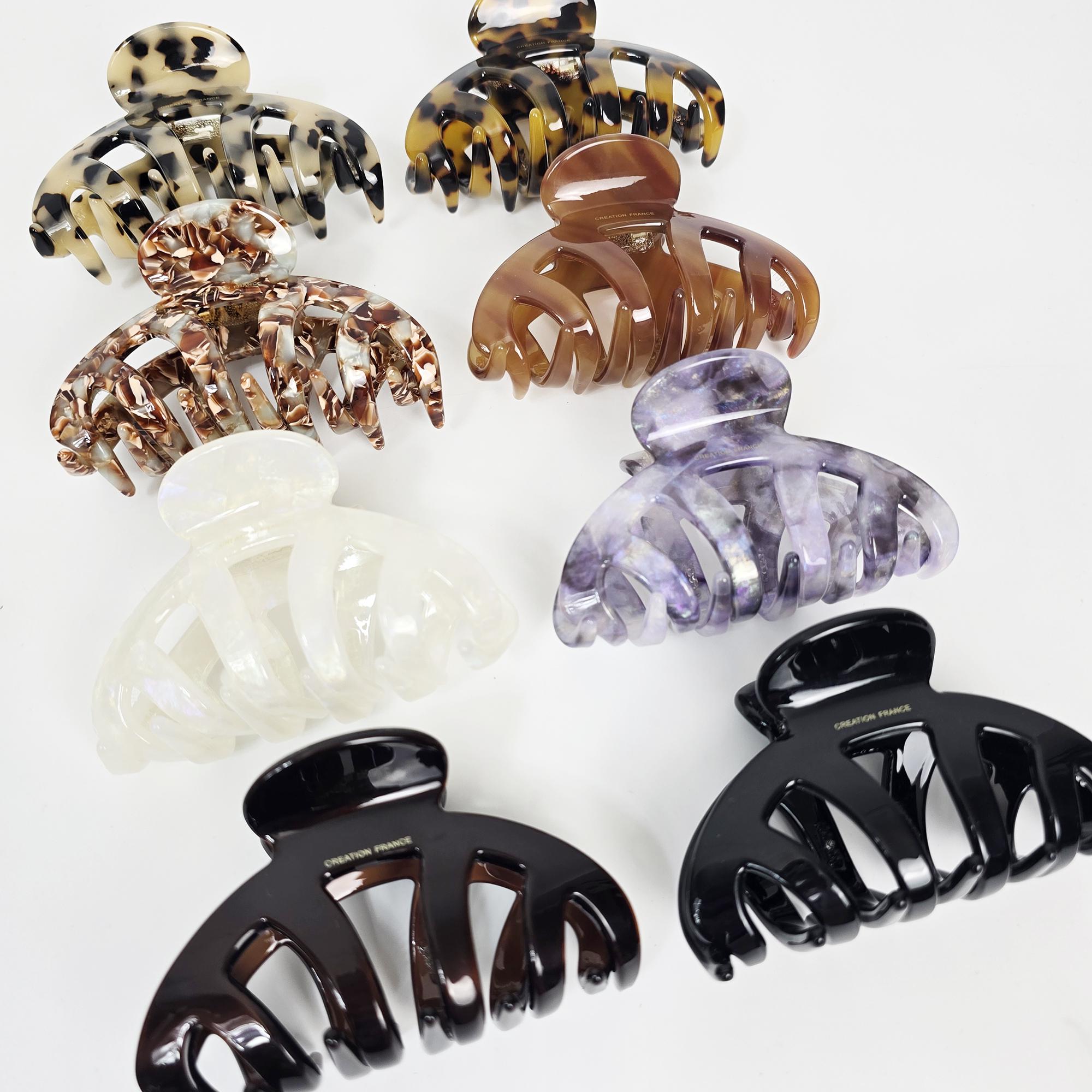 Glossy cellulose acetate hair claw clip in tortoise shell and iridescent marble patterns. Large 4.1 inch curved bridge design with strong interlocking teeth, perfect for securing thick hair updos and french twists.