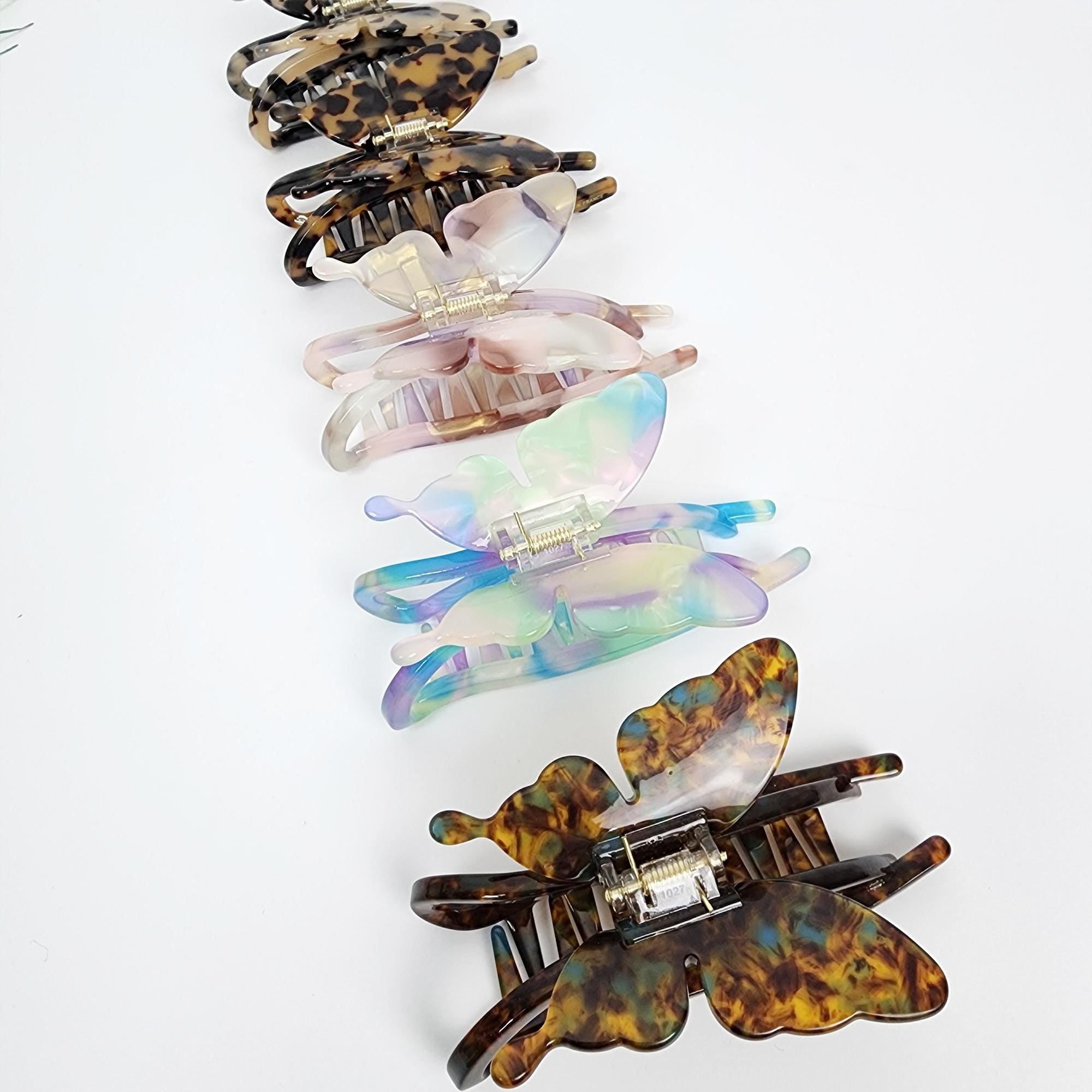 Cellulose acetate butterfly hair claw clip in tortoise shell and iridescent marble patterns for elegant updos and thick hair styling.