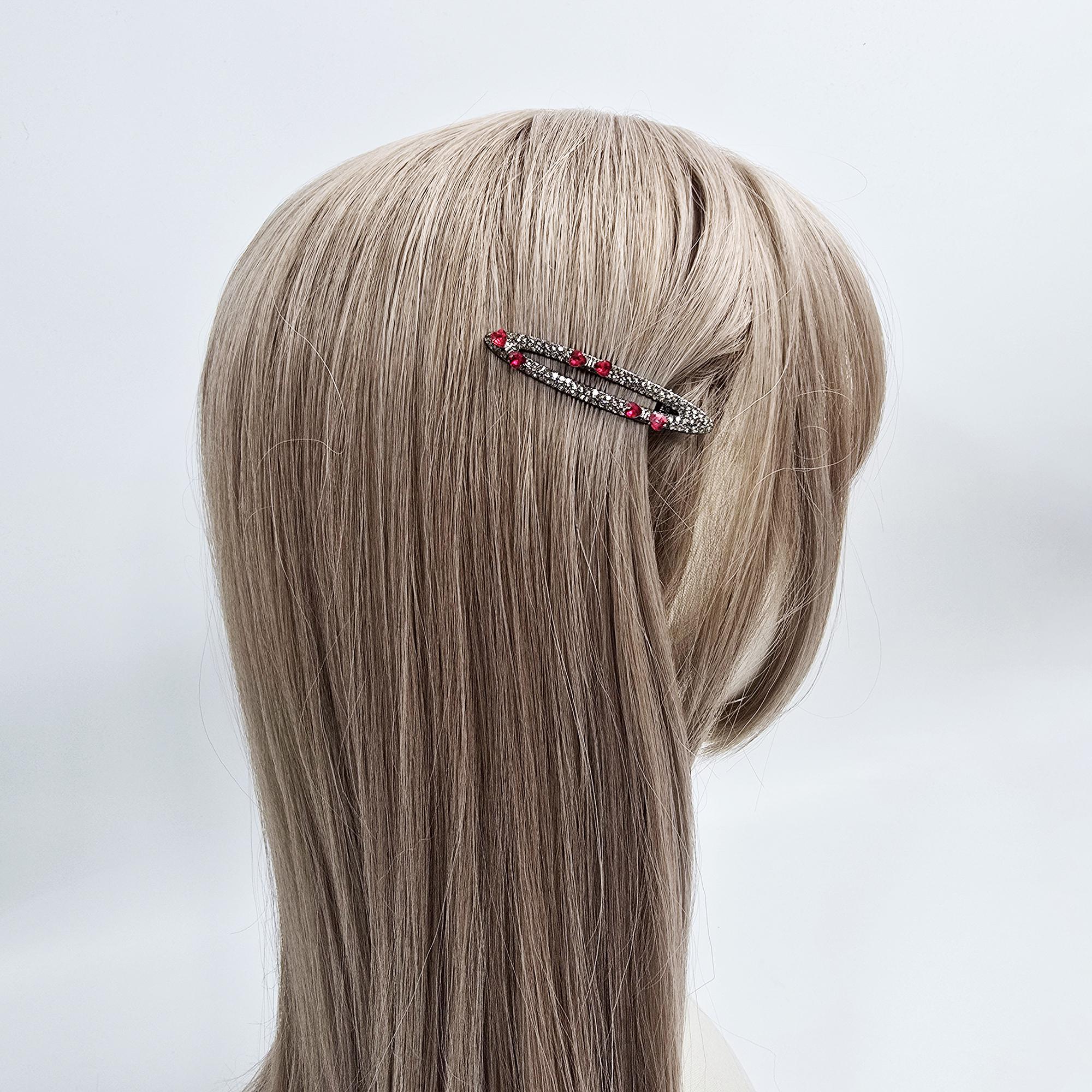 Small oval alligator hair clips in dark gunmetal finish, fully paved with sparkling rhinestones. Available in clear crystal or red heart accent designs for side bangs.
