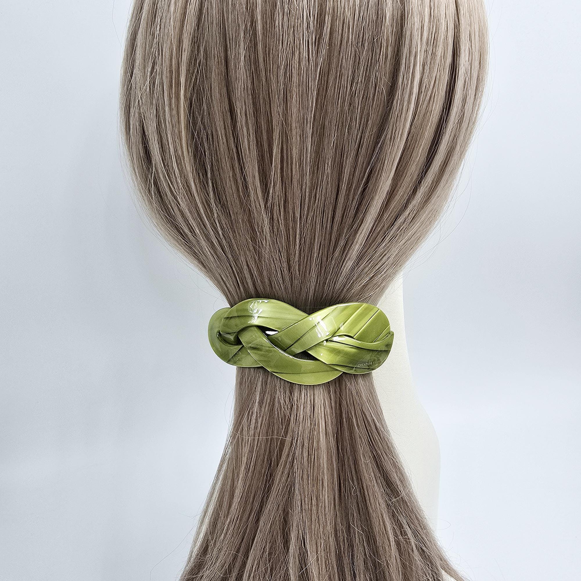 Cellulose acetate hair barrette with an elegant triple twist design. 3.5 inch automatic french clip with removable inner rod for adjustable hold. Perfect for half-up hairstyles. A lime green braided hair tie. The hair tie is made of a woven material and has a glossy finish. It is shown on a mannequin with light brown hair.