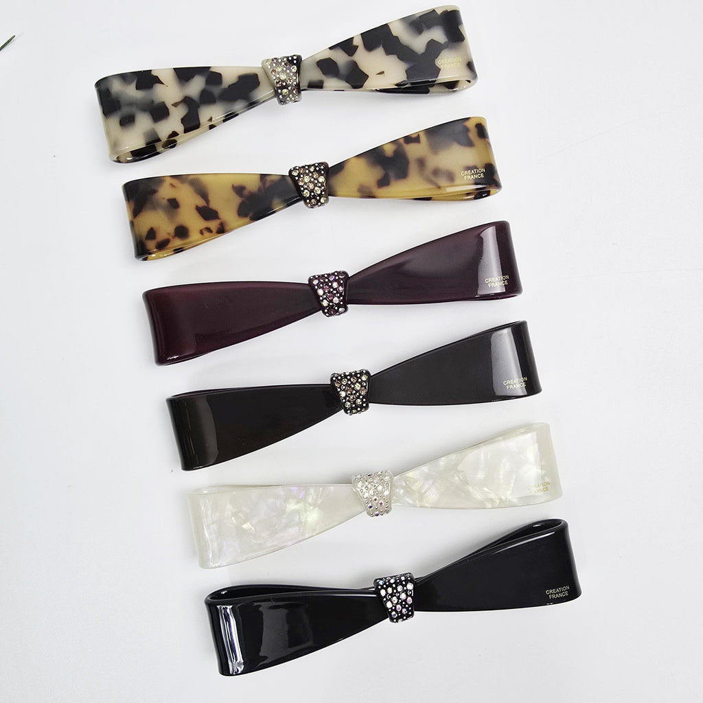 Cellulose acetate long slim hair barrette with a rhinestone bow tie accent. 4.9 inch automatic french clip suitable for ponytails or half-up styles. Elegant hair accessory.