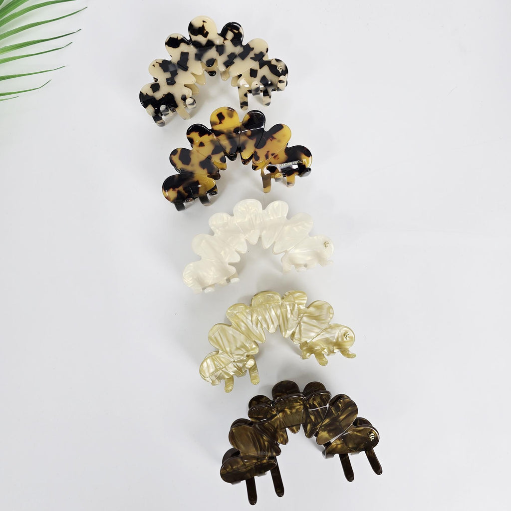Large 4.1 inch cellulose acetate hair claw clip in a scalloped crown shape. Features pearlescent and tortoise shell patterns with strong interlocking teeth, perfect for securing updos and french twists on medium to thick hair.