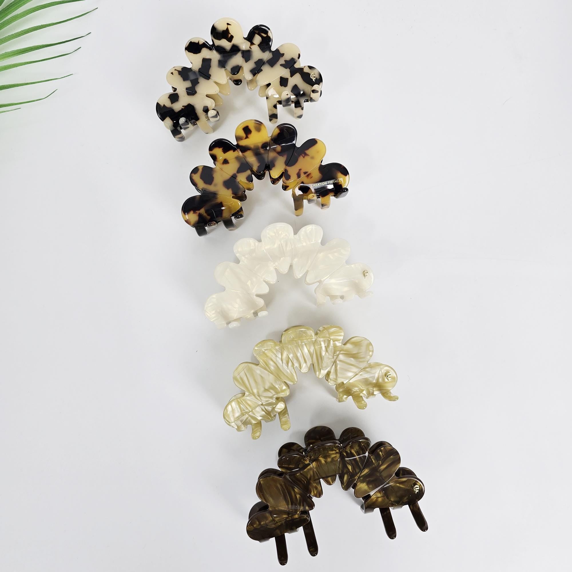 Large 4.1 inch cellulose acetate hair claw clip in a scalloped crown shape. Features pearlescent and tortoise shell patterns with strong interlocking teeth, perfect for securing updos and french twists on medium to thick hair.