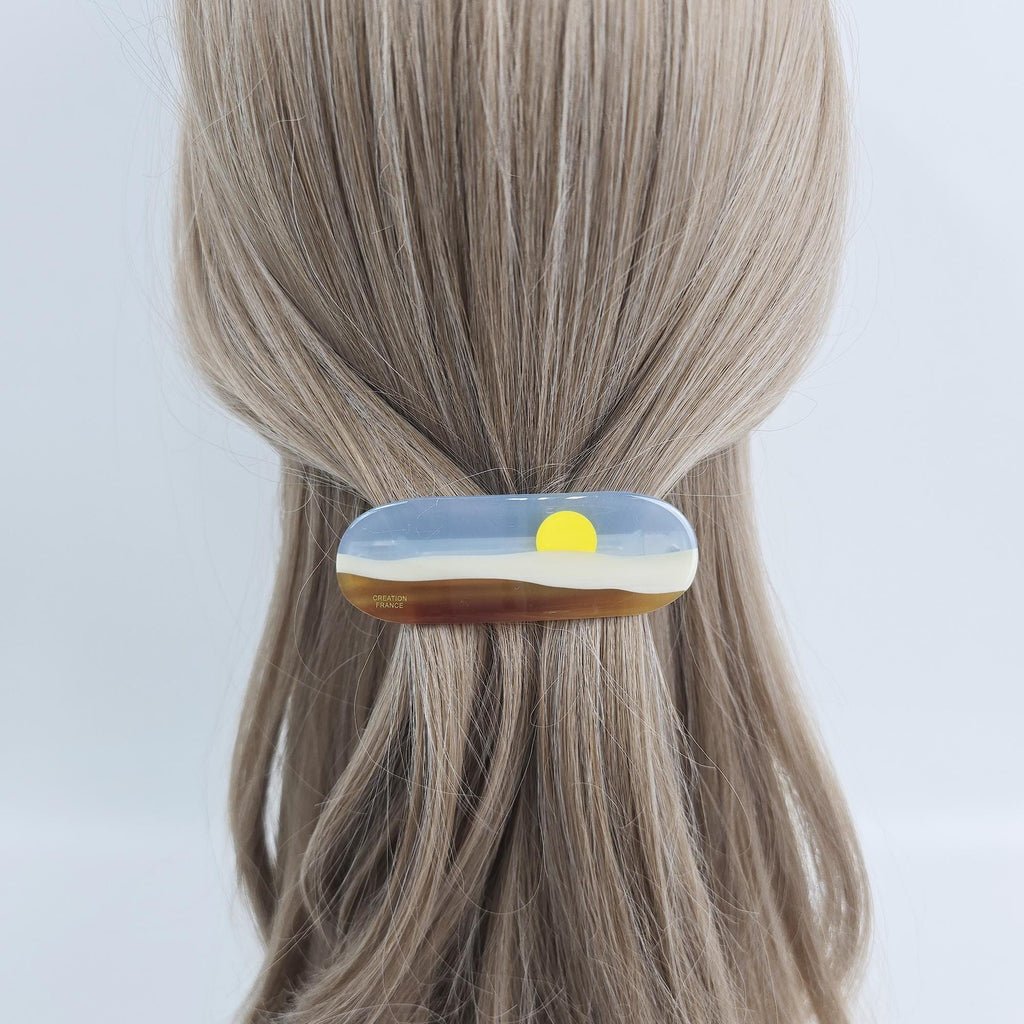 Cellulose acetate hair barrette with sunset landscape design. 3.5 inch french clip with blue sky and brown hills for women half up style. A brown and blue hair clip with a yellow sun design