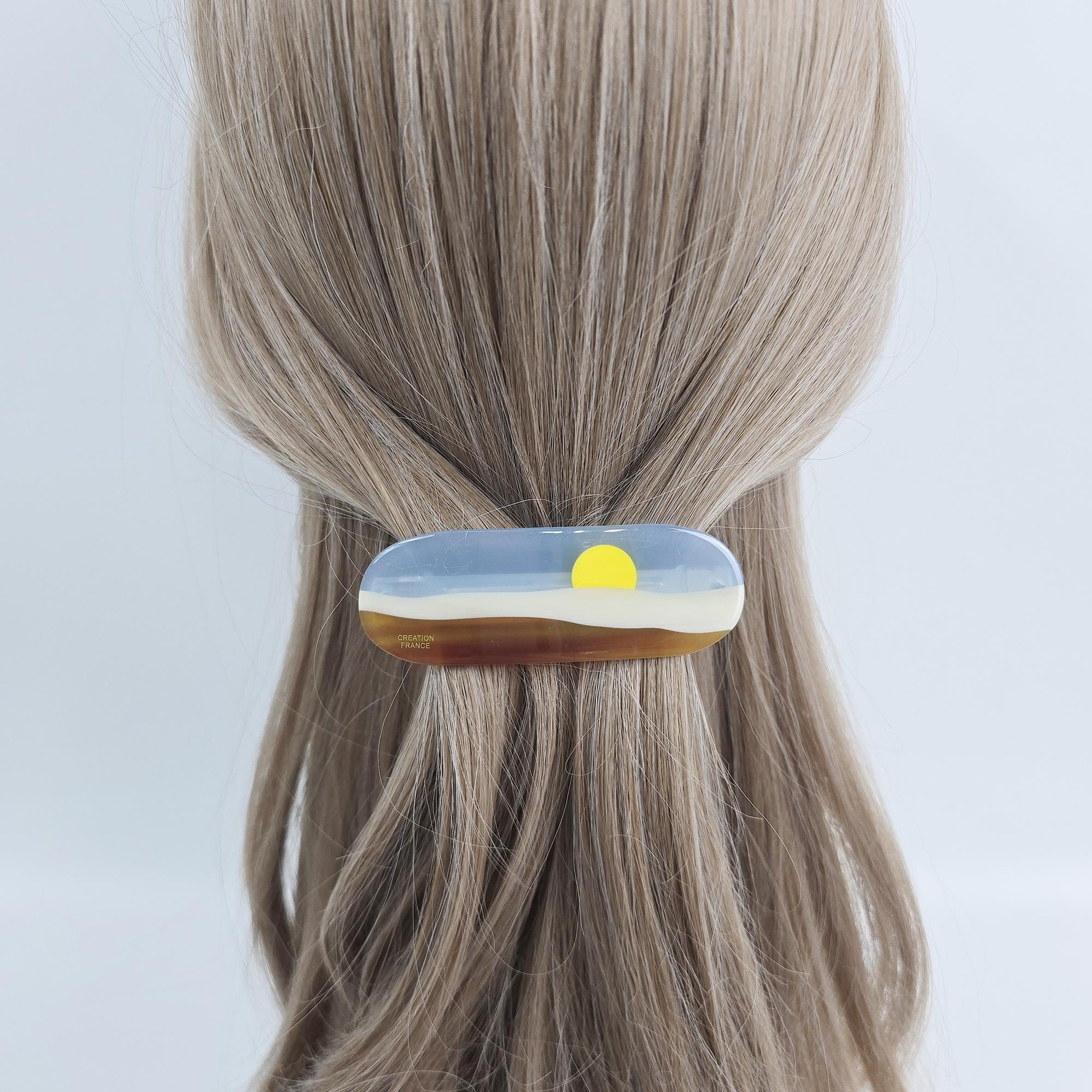 Cellulose acetate hair barrette with sunset landscape design. 3.5 inch french clip with blue sky and brown hills for women half up style. A brown and blue hair clip with a yellow sun design